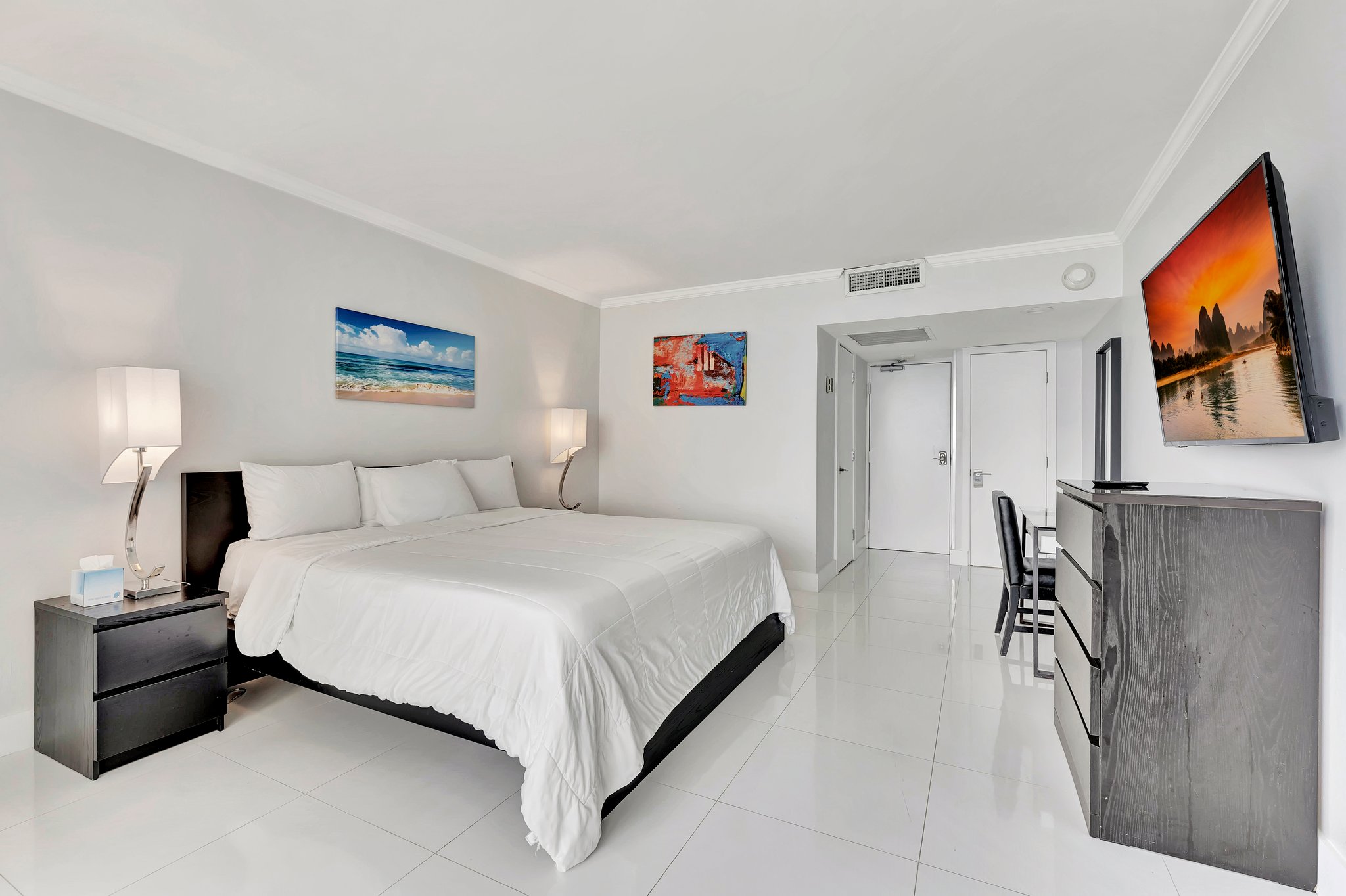 Side angle view of the room with bed, artwork, and ambient lighting