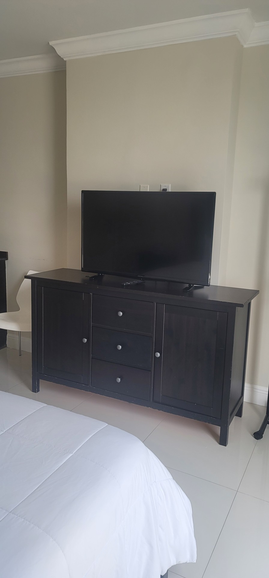 Flat-screen TV on a dark wood dresser in the guest room