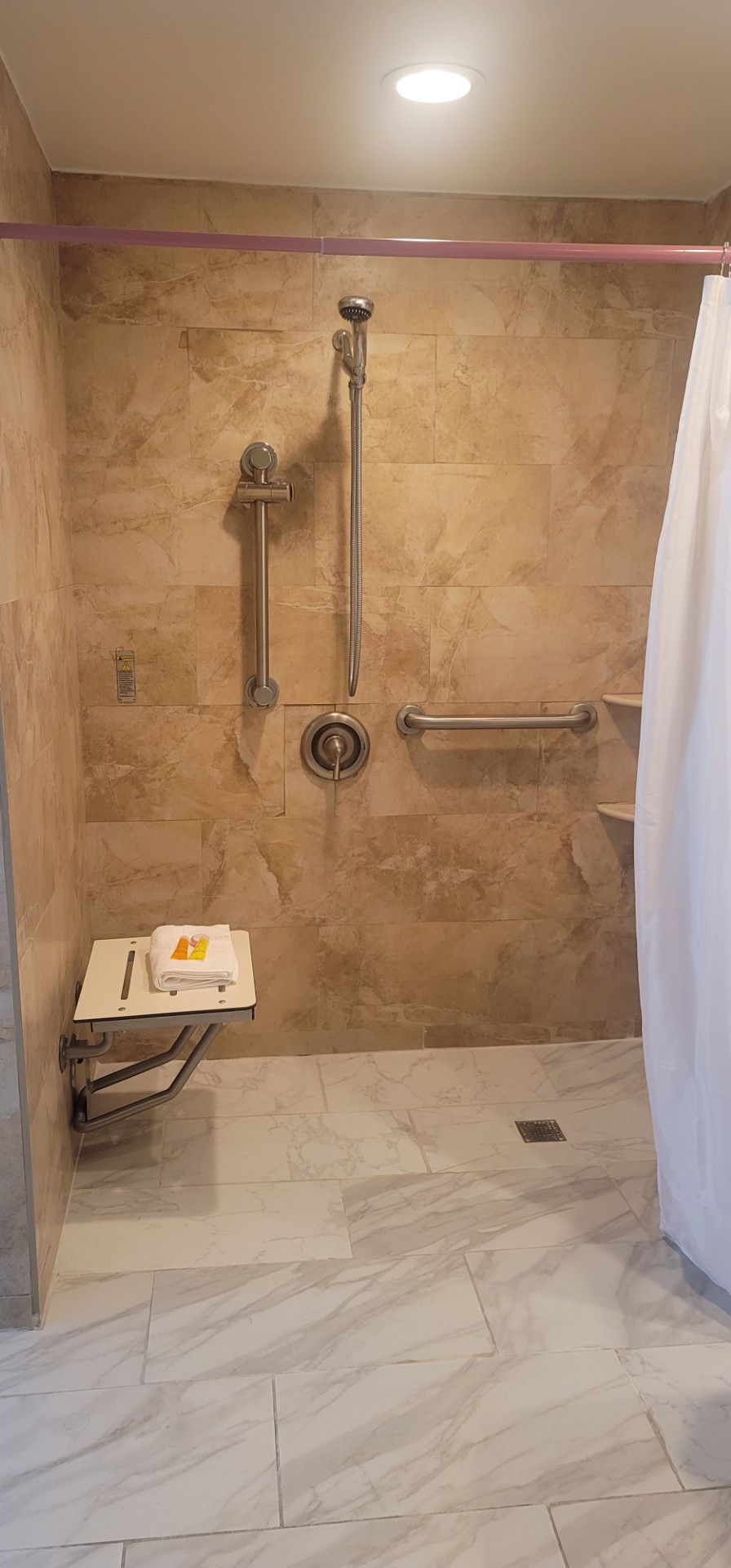 Guest-room shower shown with grab bars and a handheld shower at Ocean Manor Beach Resort