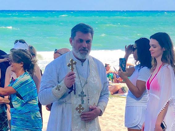 Priest holding a cross during a beach blessing near the Miracle Cross in Fort Lauderdale