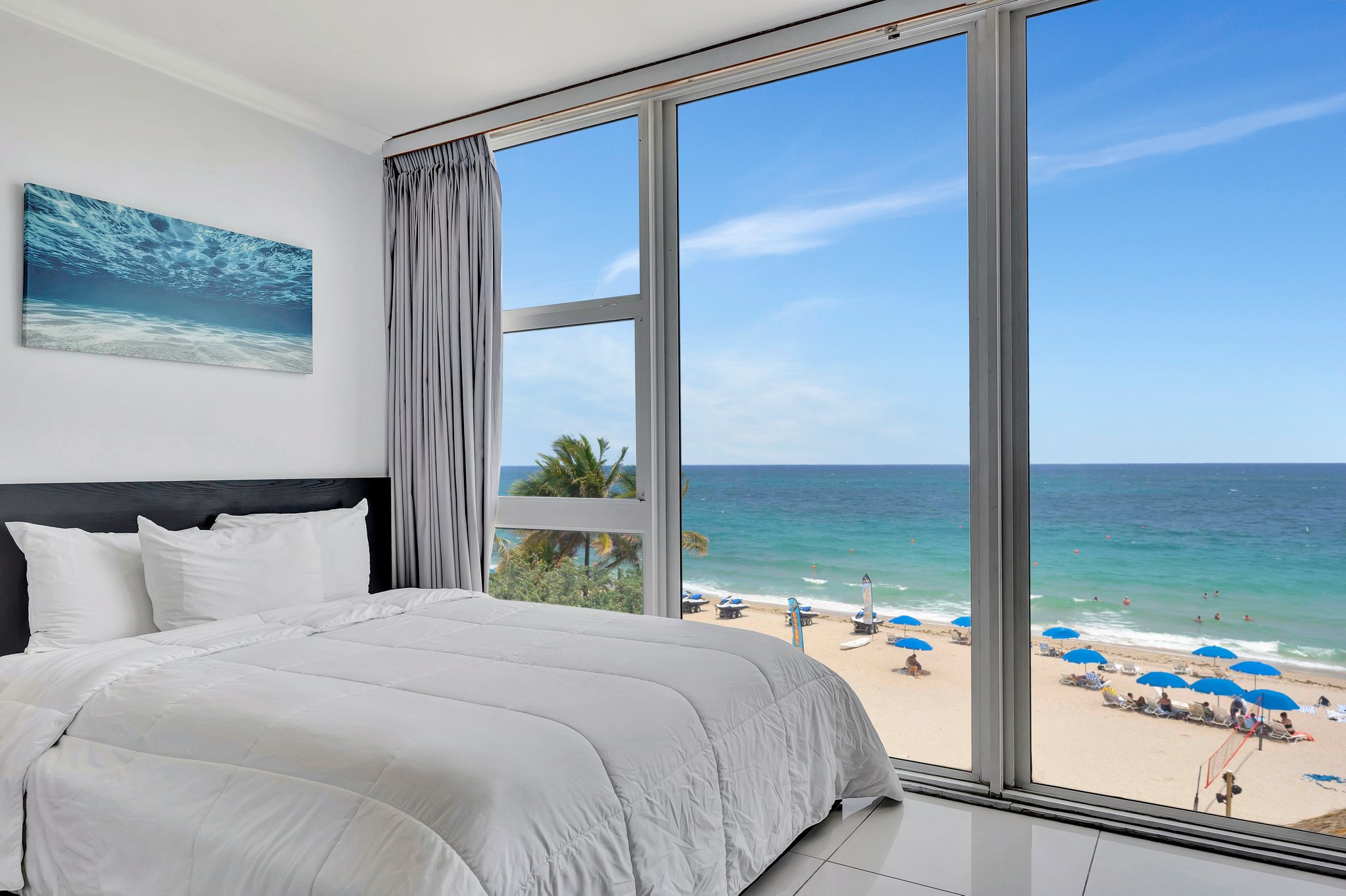 Deluxe Efficiency bed with beach backdrop at Ocean Manor