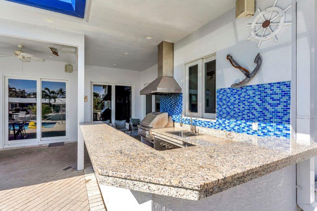 Outdoor kitchen and grill area at 2870 NE 9th Street Pompano Beach luxury mansion with granite counter and pool view