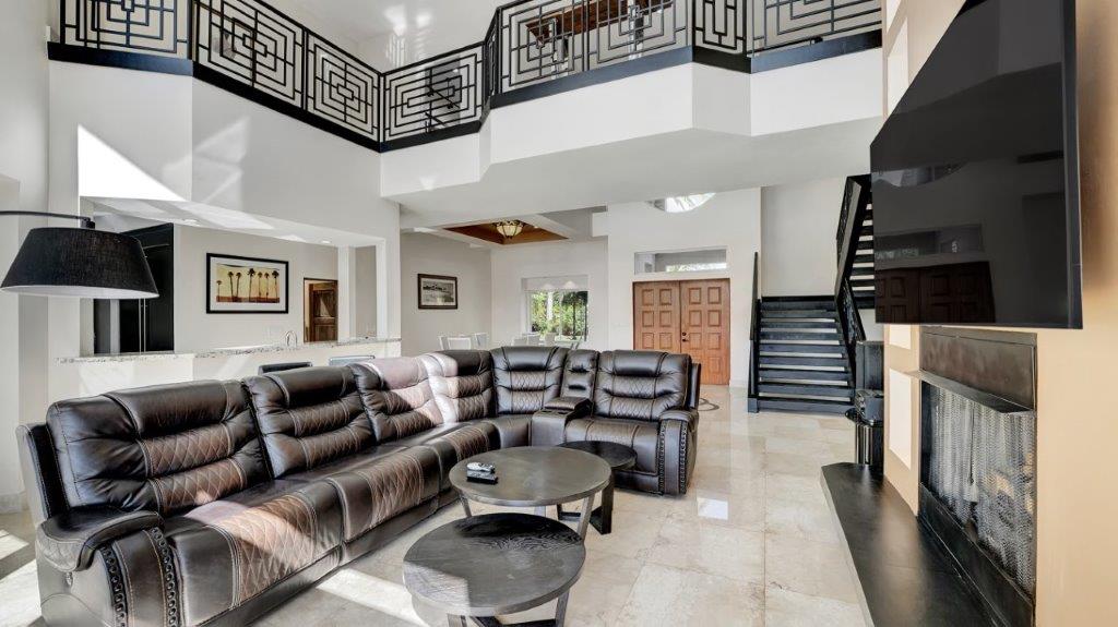 Spacious living room at 2886 NE 26th Place Fort Lauderdale luxury mansion with leather sofa, fireplace, and high ceilings
