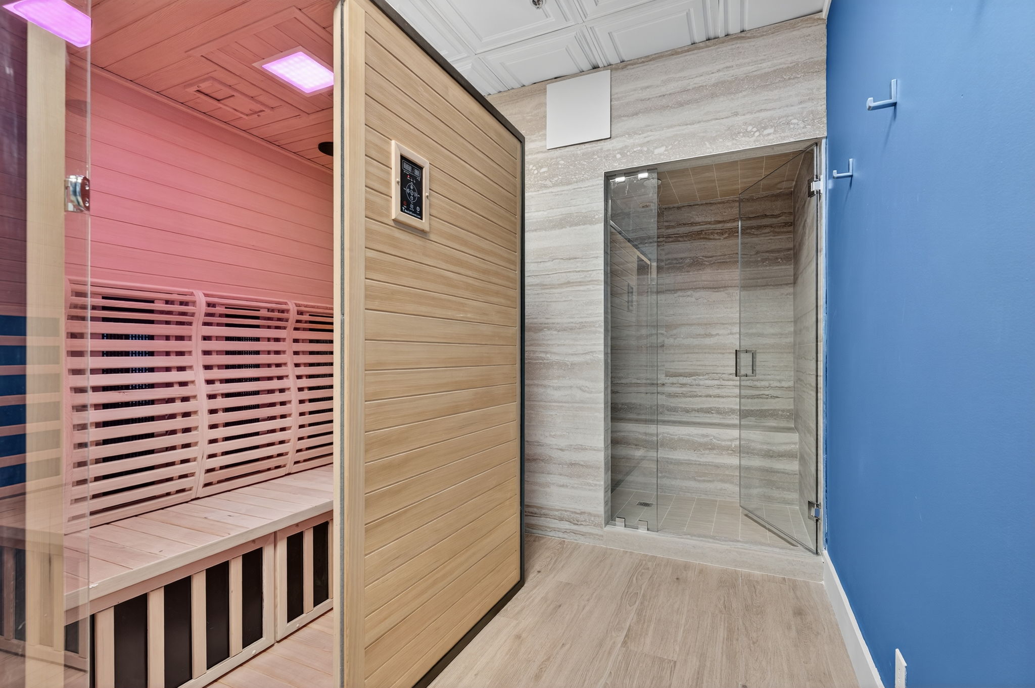 Infrared sauna with pink chromotherapy lighting next to a marble steam room at OM Steam Wellness, Ocean Manor Resort