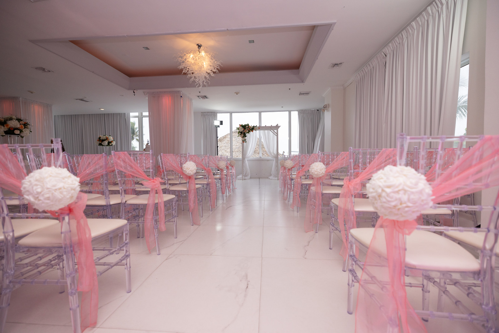 Romantic indoor wedding ceremony setup with pink decorations in the ballroom